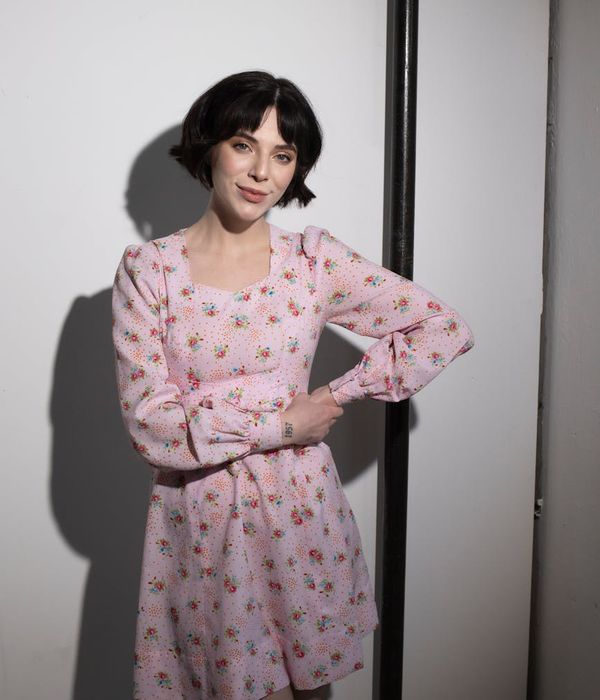 Woman in a serene yoga pose in a dark room with soft pink light.